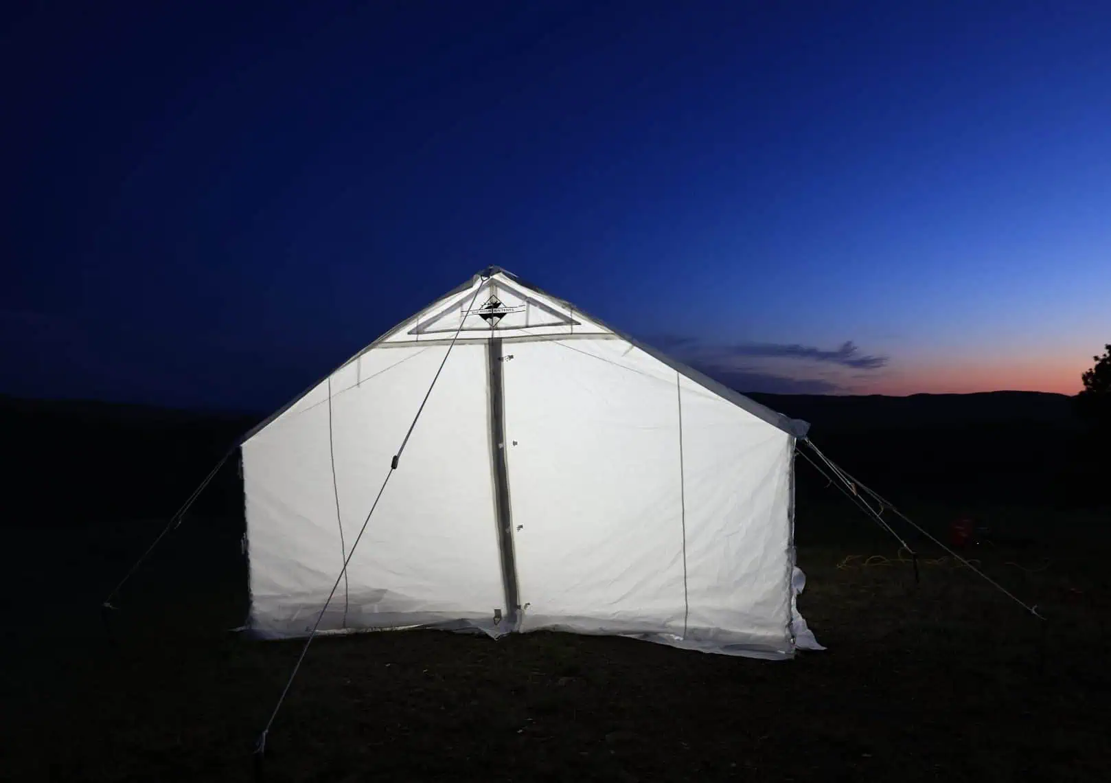 standard model wall tent lit up at night