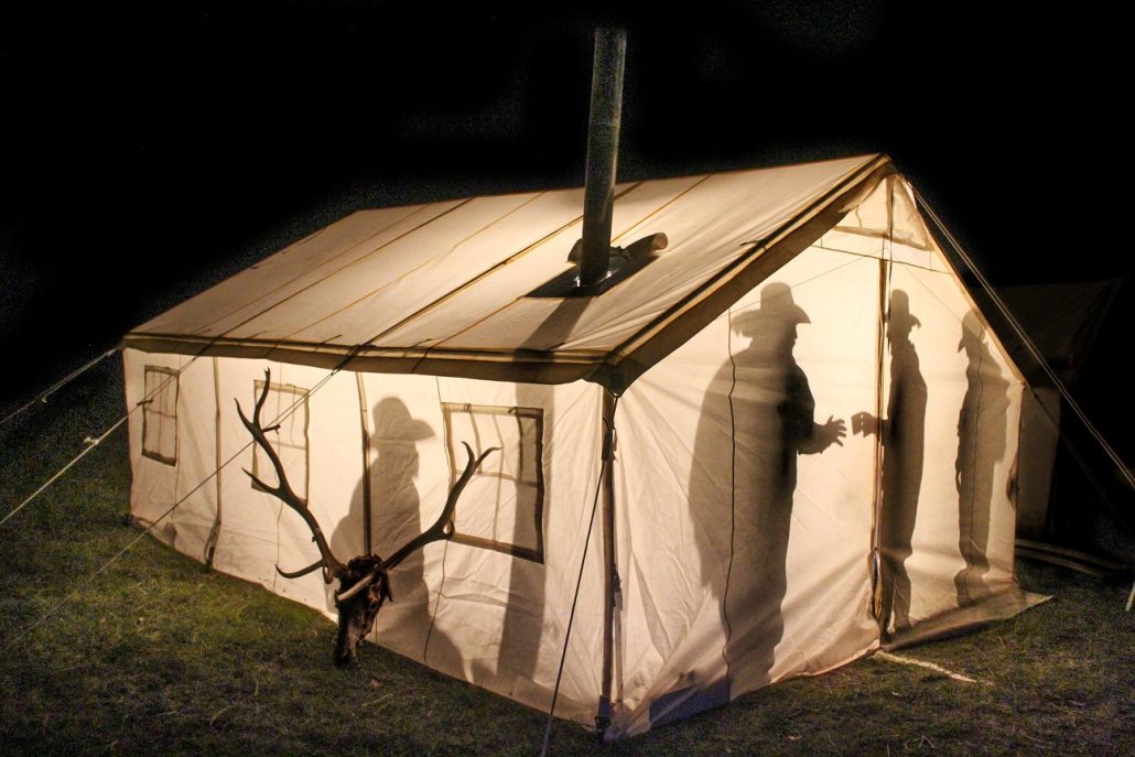 people talking in a canvas tent at night